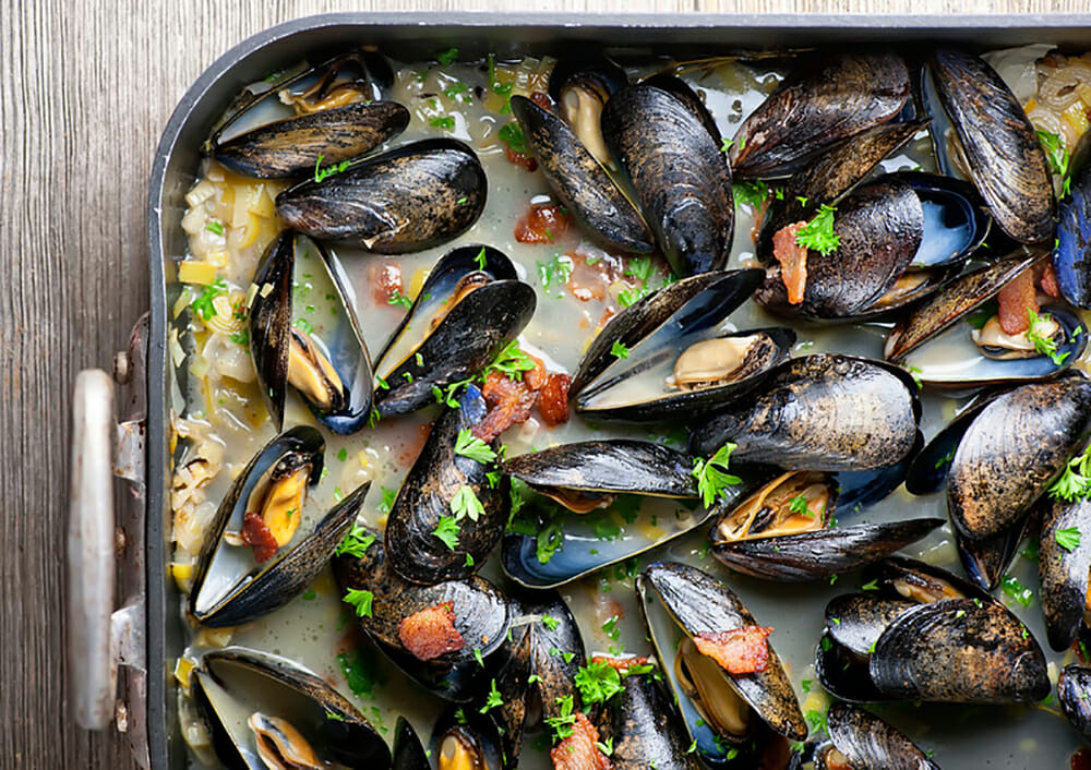 Mussels with white wine and bacon in a roasting pan.