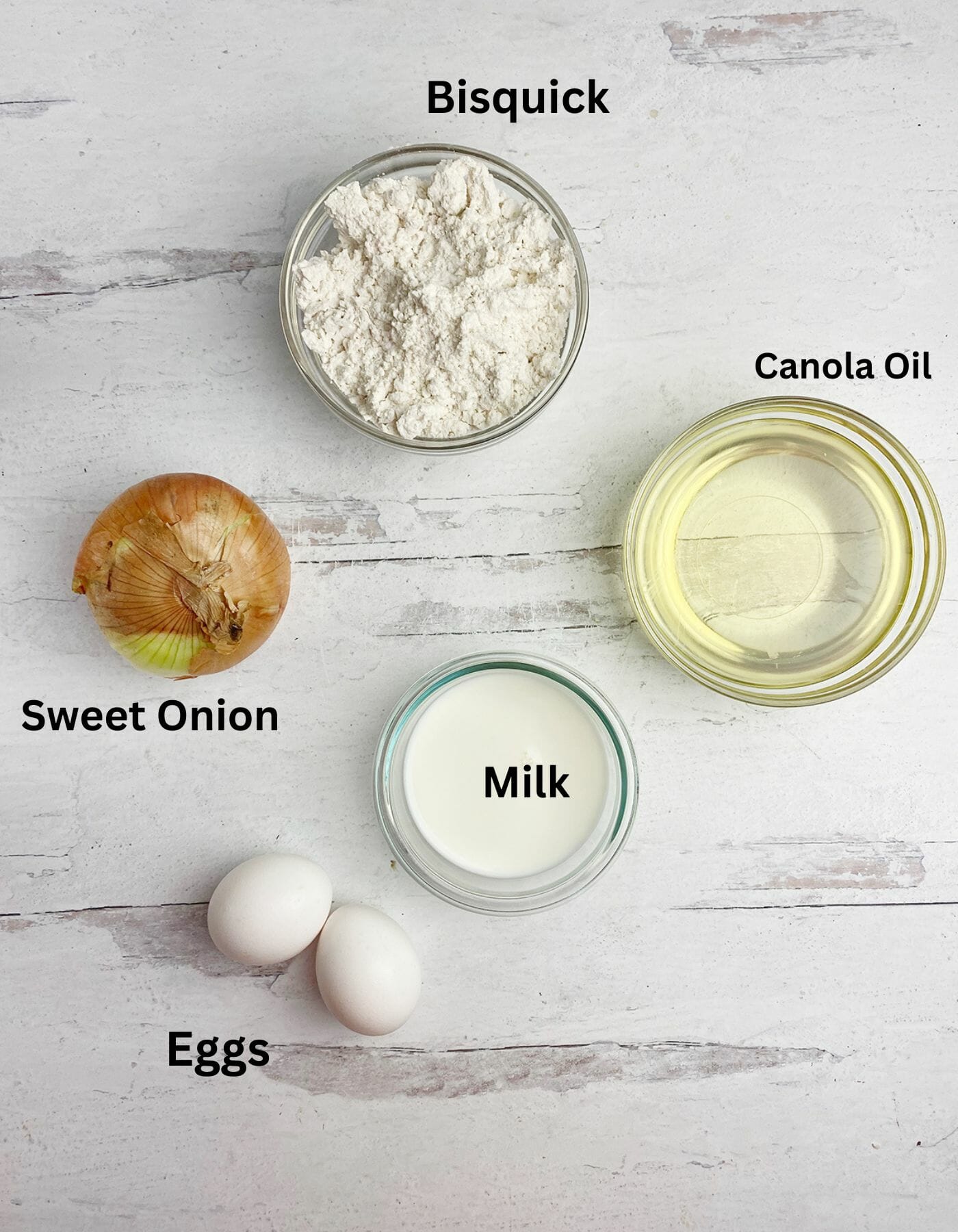 Pancake batter onion rings ingredients on a wooden counter.