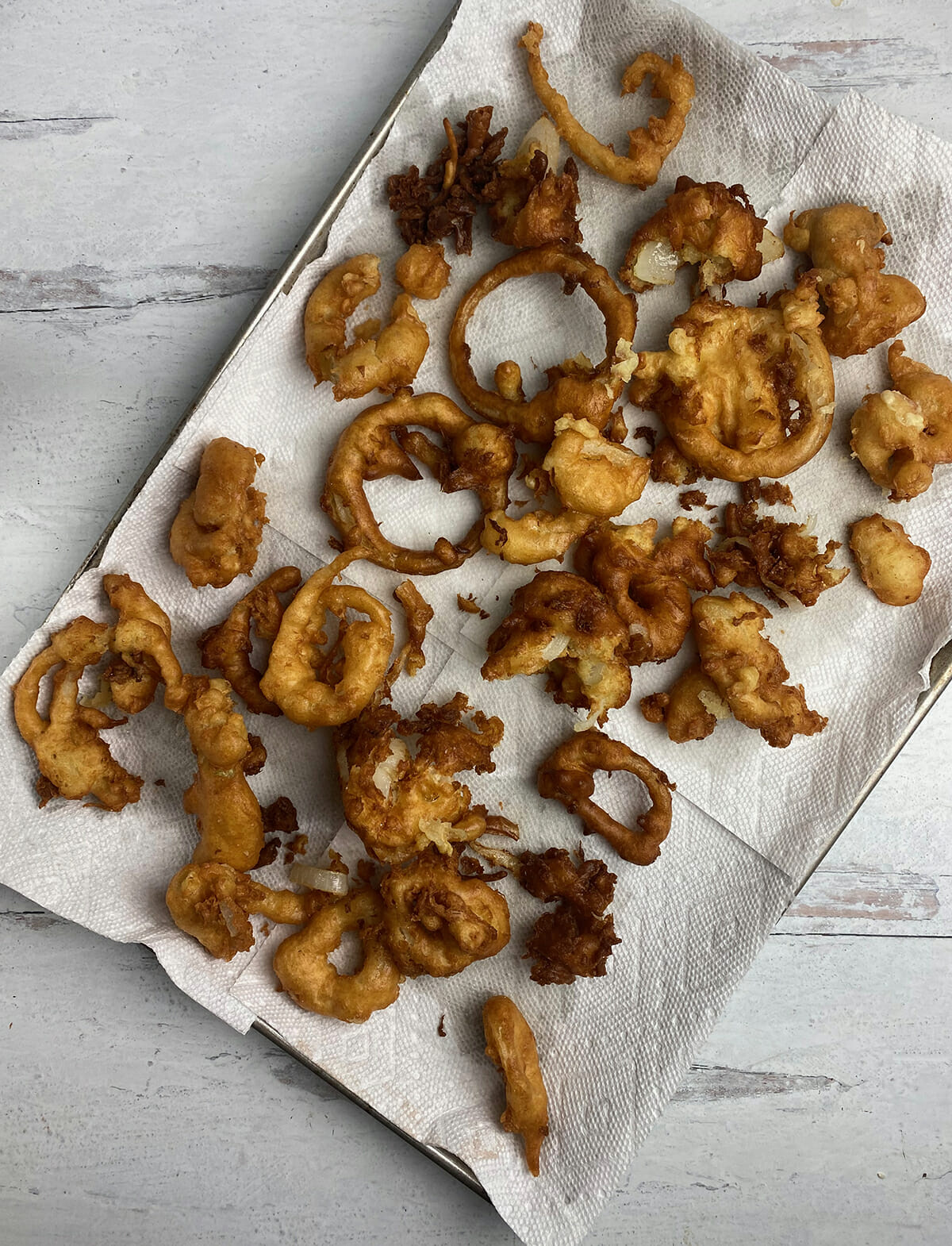 Pancake onion rings draining on paper towels.