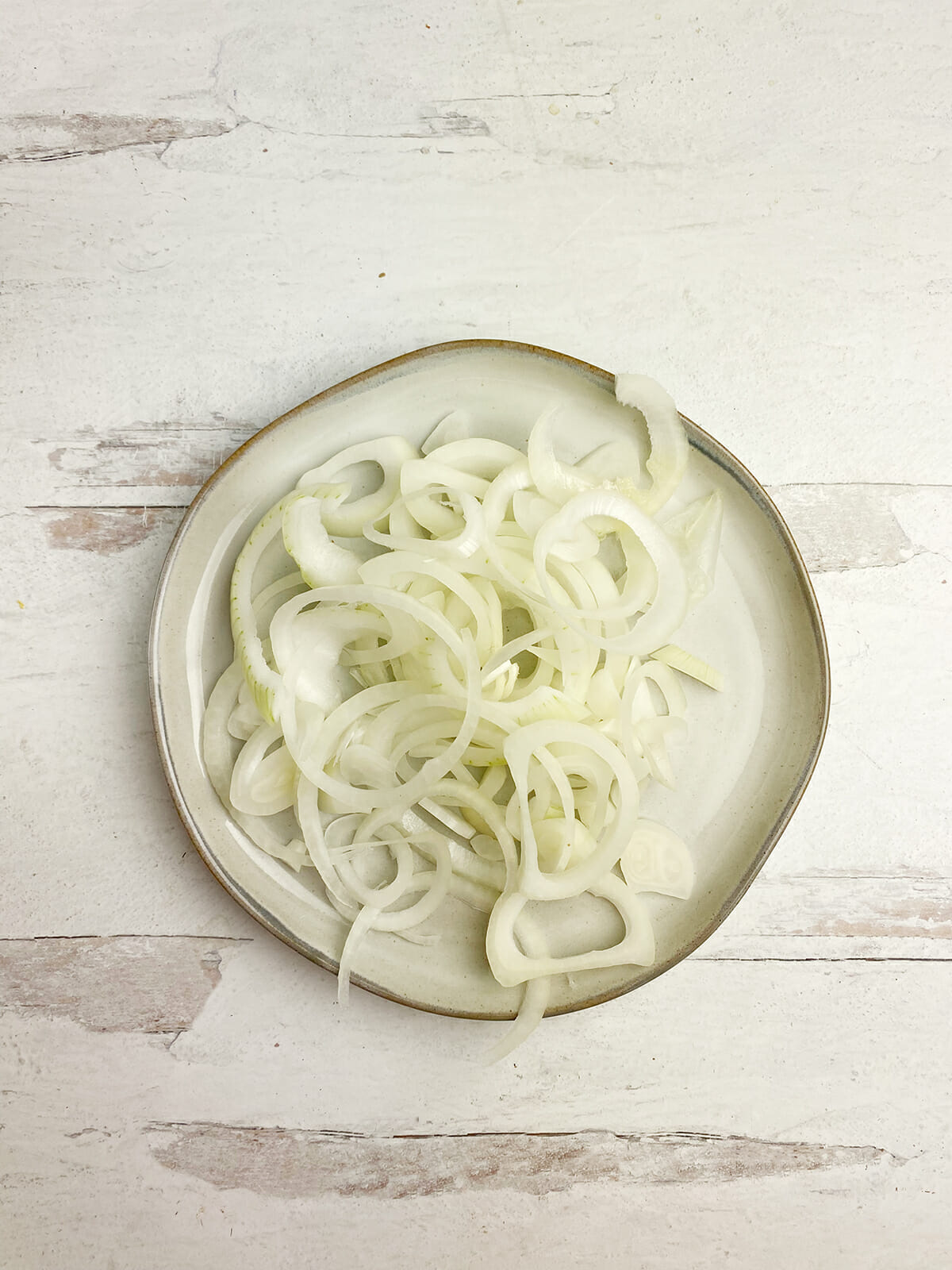Sliced and peeled onions on a plate.