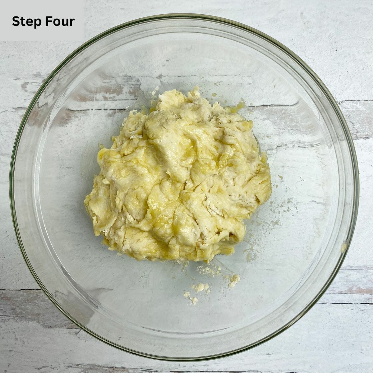 A ball of un-risen pizza dough in a mixing bowl.