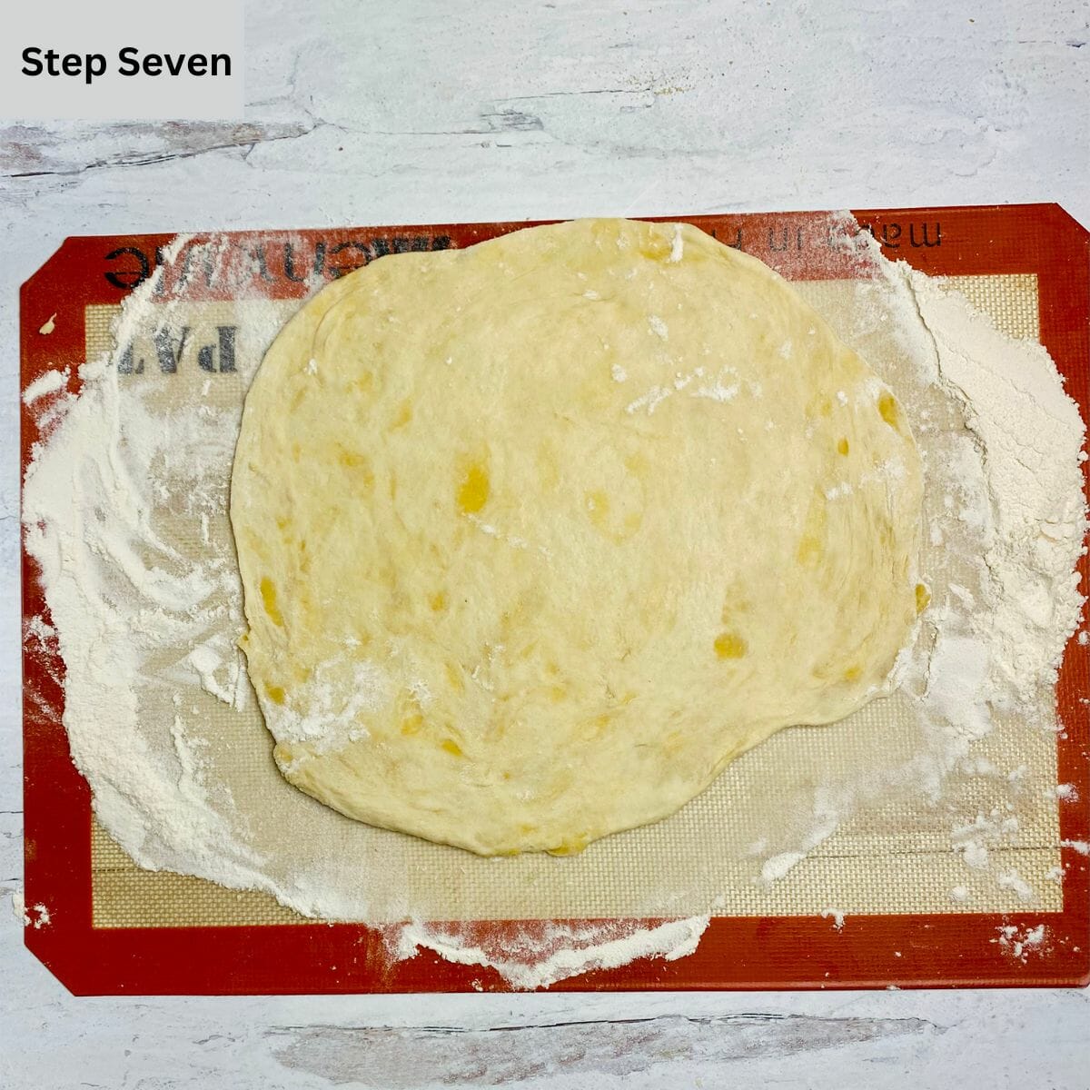 Rolled out pizza dough on a silicone mat.