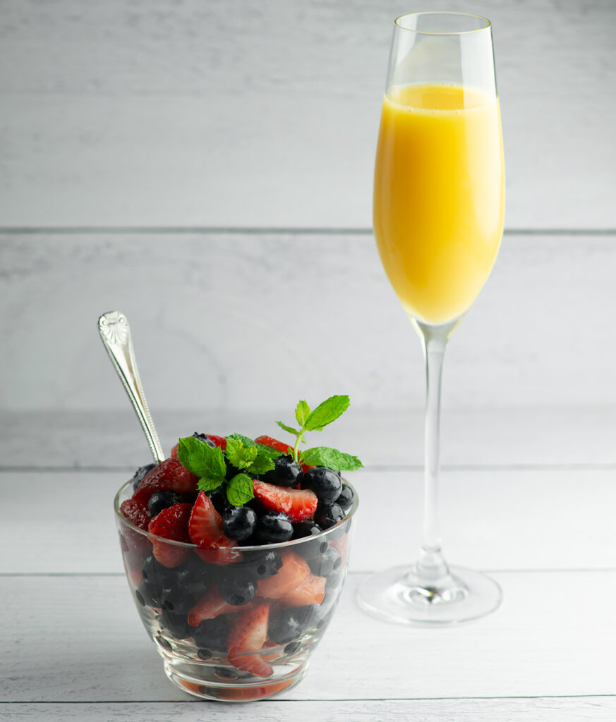 Mimosa fruit salad with a glass of mimosa.