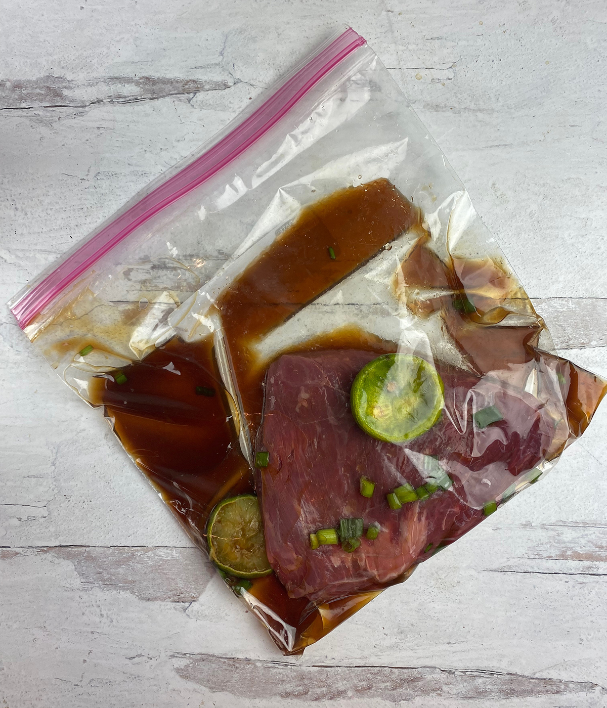 Rum steak marinating in a plastic bag.