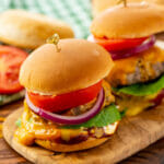 Steamed cheeseburgers on a wooden board.