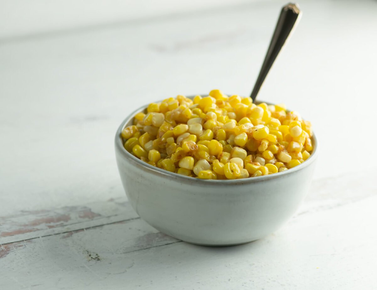 Buttered skillet corn in a bowl with a spoon.