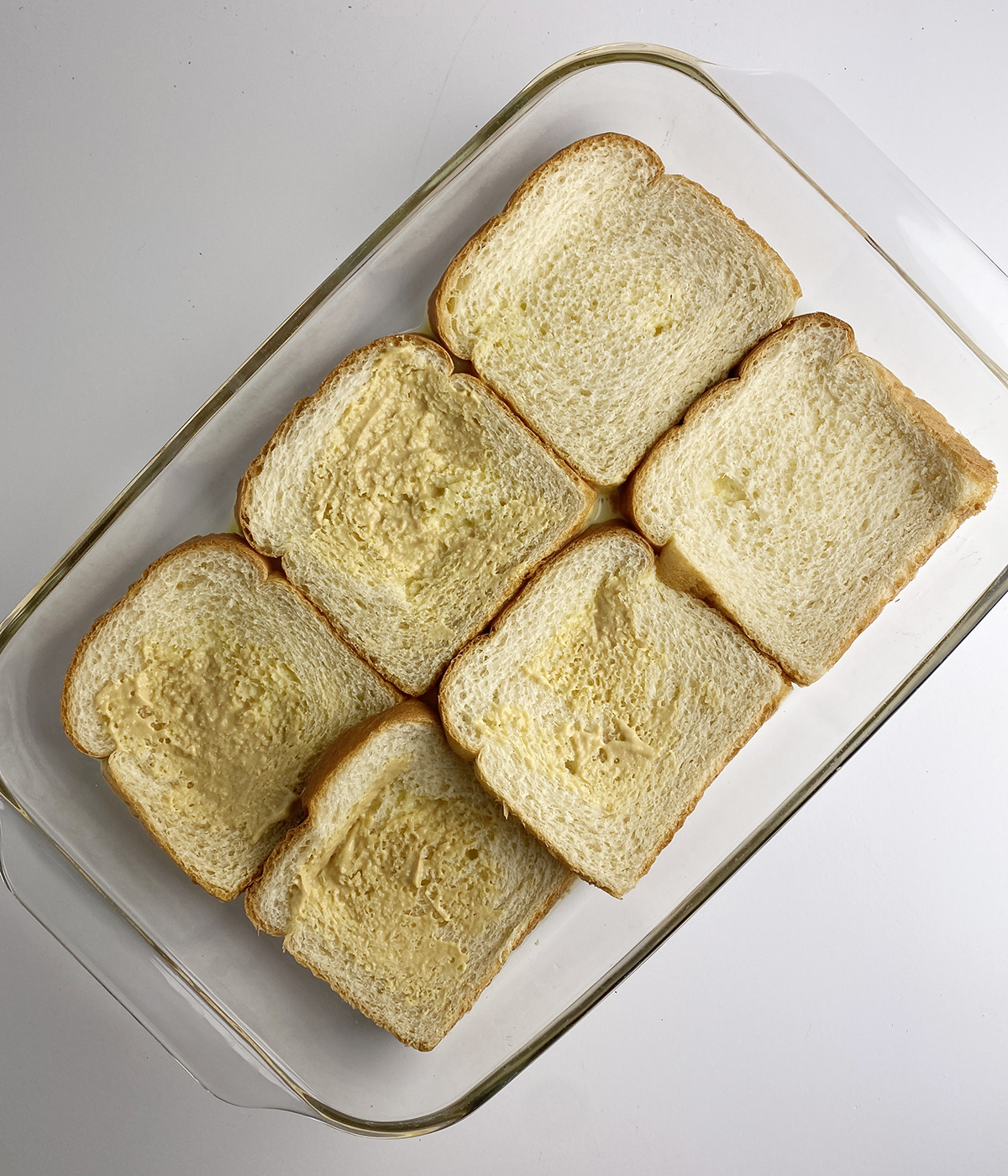 Bread with mustard in a casserole dish.