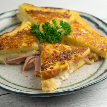 French toast grilled ha and cheese on a plate with parsley.