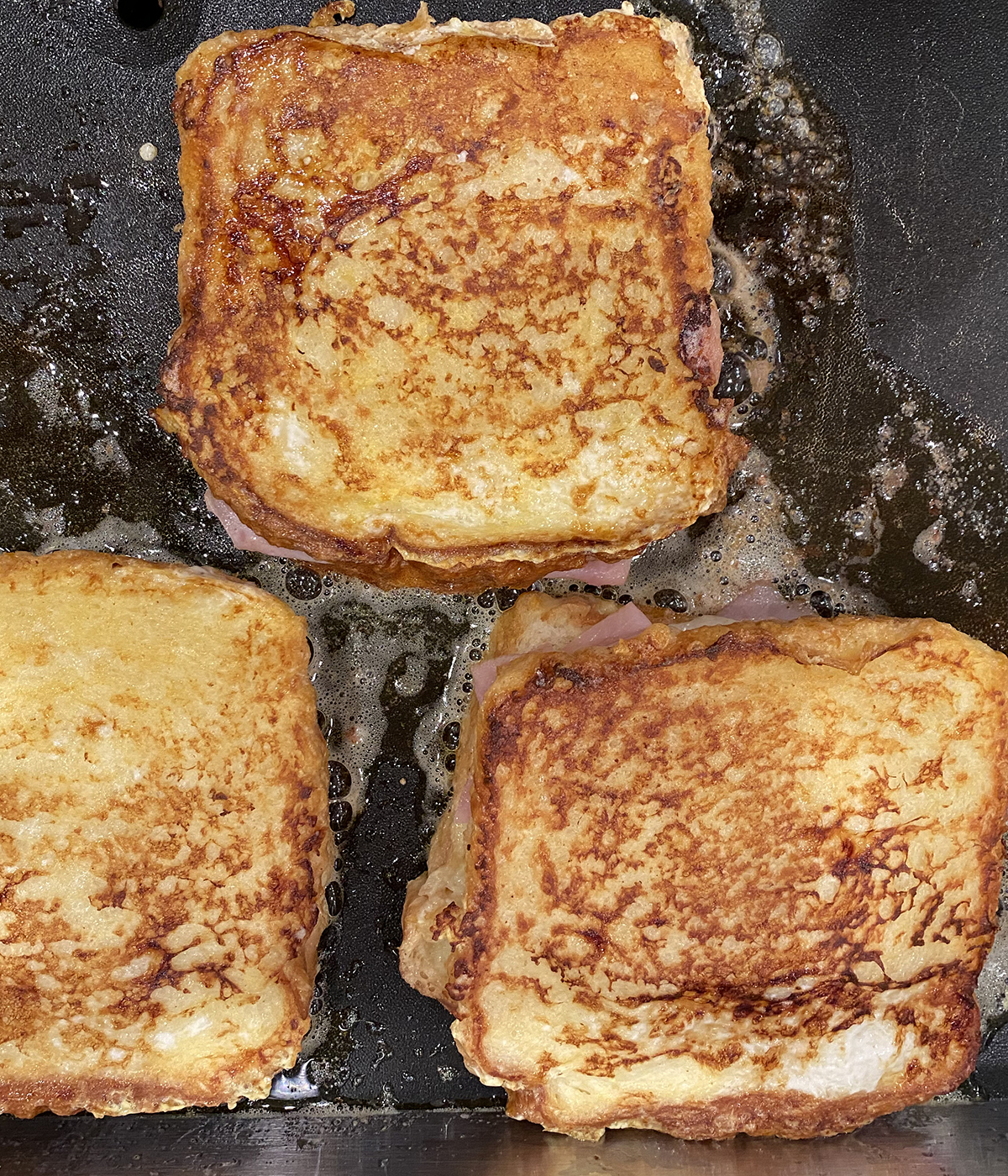French toast grilled ham and cheese sandwiches on a griddle.