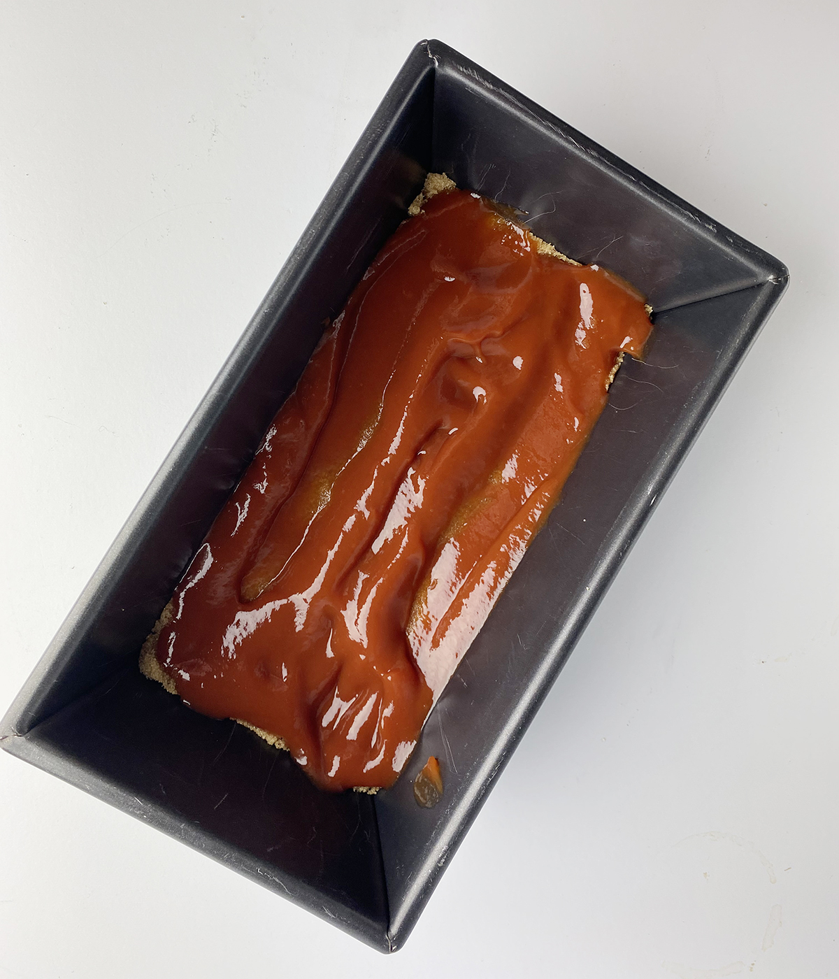 Ketchup layer in a loaf pan for brown sugar meatloaf.