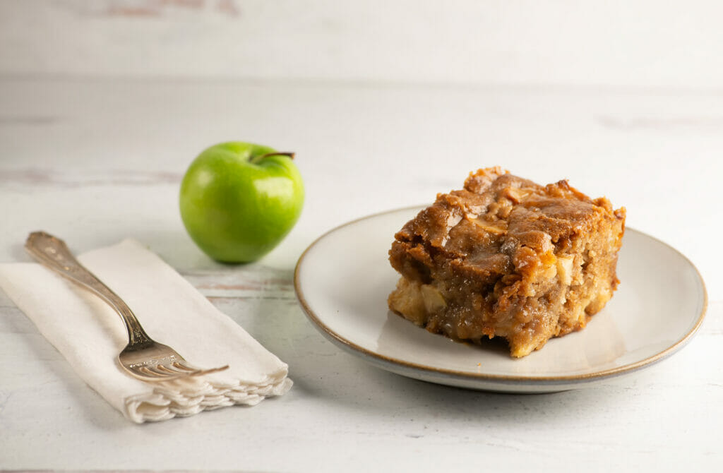 Sticky caramel apple cake on a plate with a fork and napkin on the side.