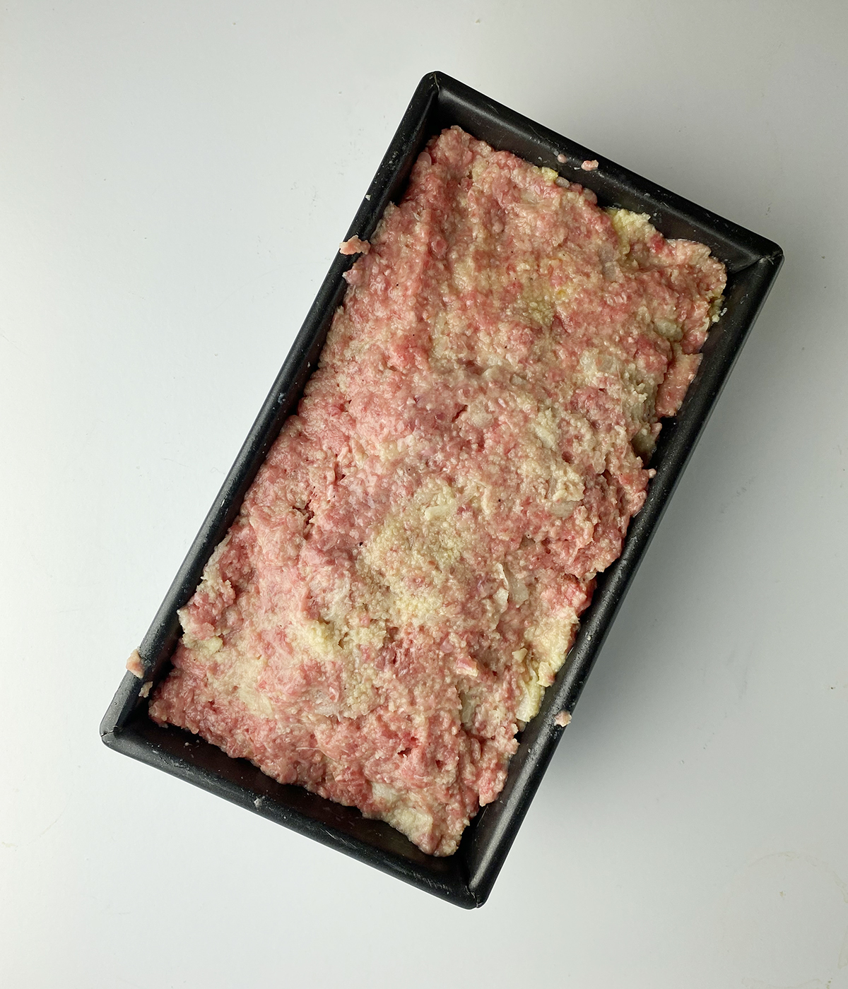 Uncooked brown sugar meatloaf in a loaf pan.