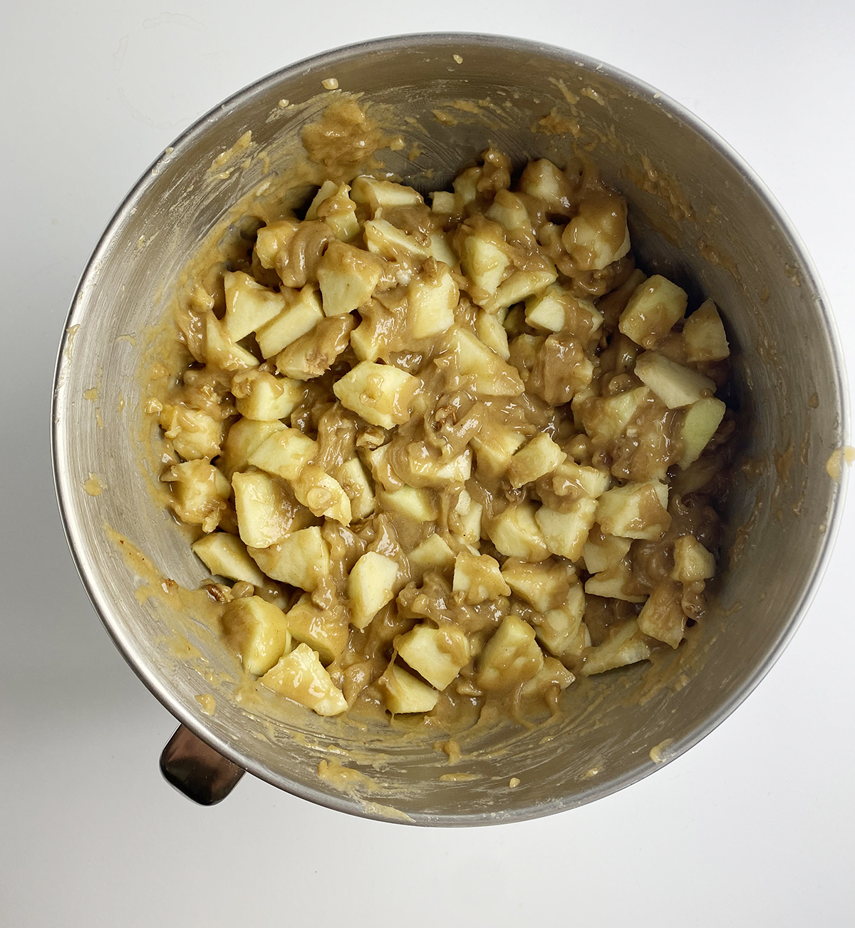 Caramel apple cake with apples mixed in in a mixing bowl.