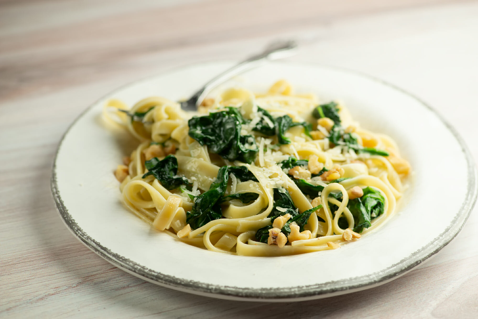 pasta with creamed spinach sauce on a plate with a fork