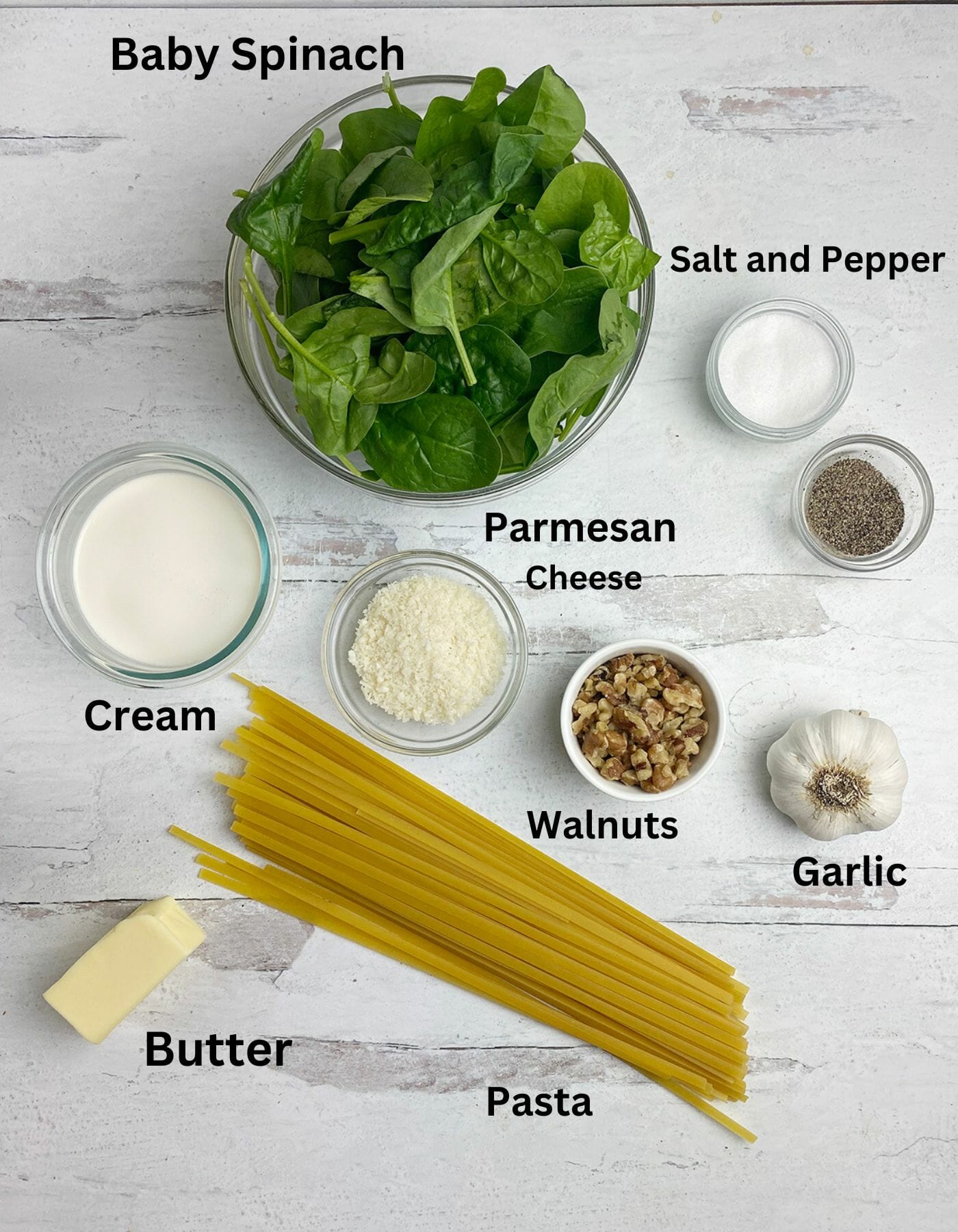 Pasta with creamed spinach sauce Ingredients on a wooden counter.