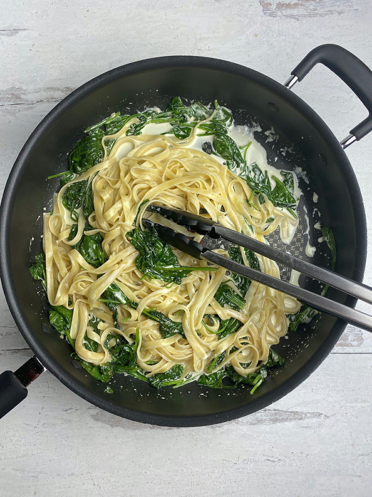 Pasta with creamed spinach sauce in a pan.