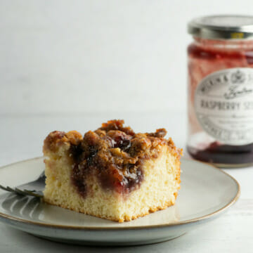 Jam cake on a plate with a jar of jam behind it.