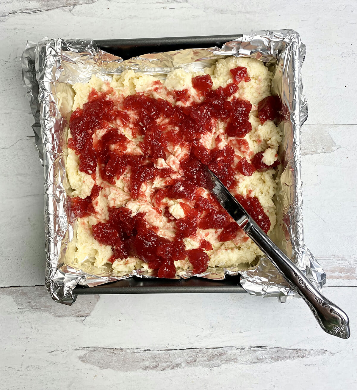 Jam cake with swirled jam in a foil lined pan.