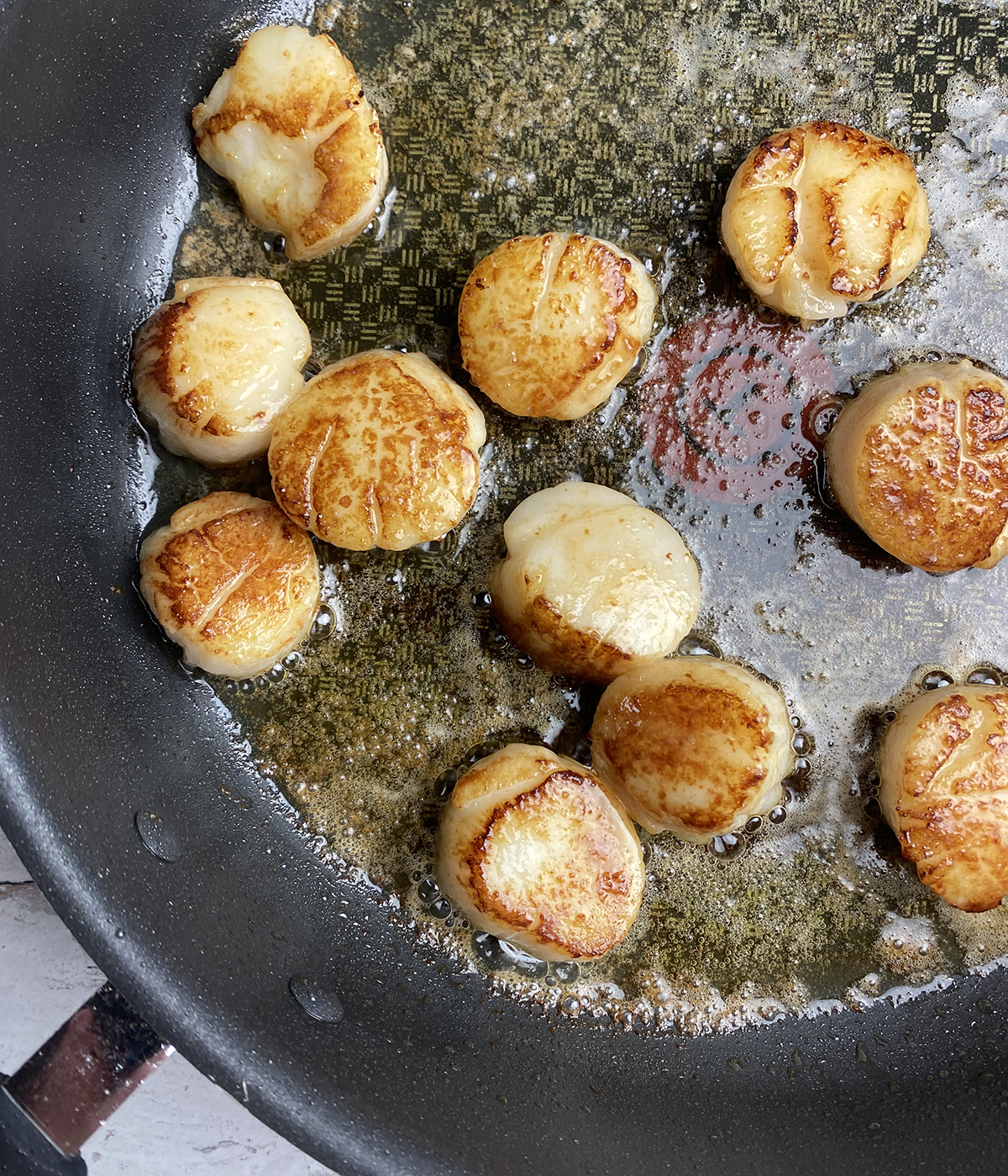 Scallops searing in a skillet.