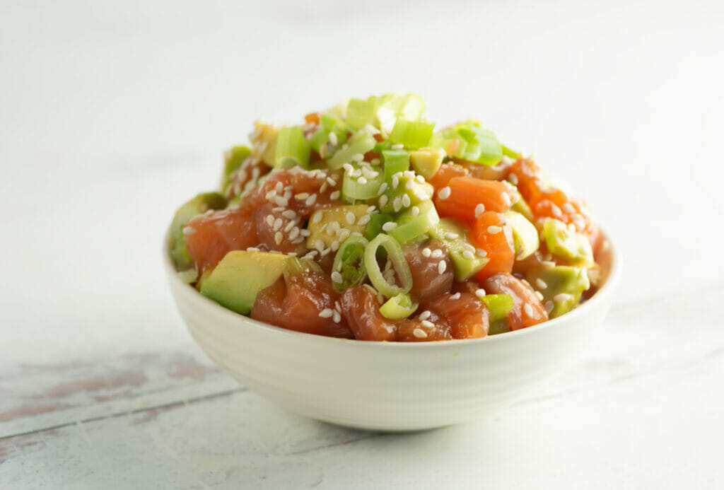 Chopped Salmon Tartare in a bowl on a wooden counter.