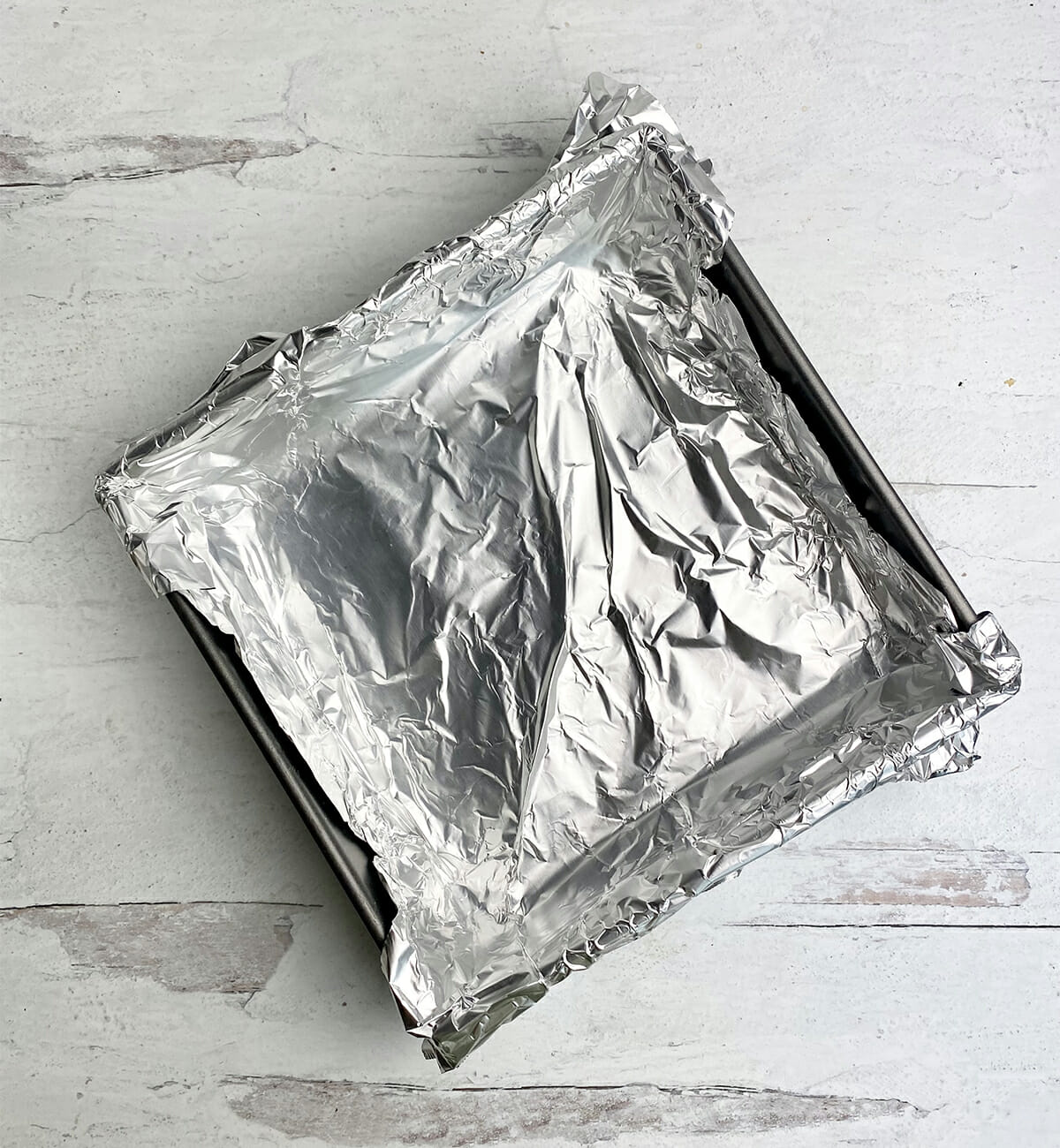 Foil lined jam cake pan on a wooden counter.