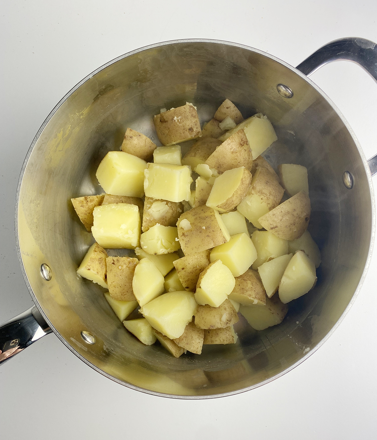 Cubed cooked potatoes in a pot.