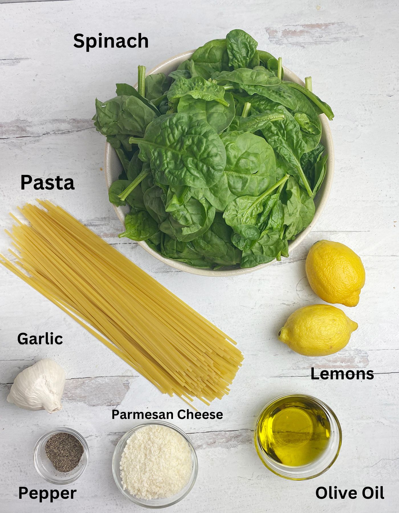 Lemon spinach pasta ingredients on a wooden counter.