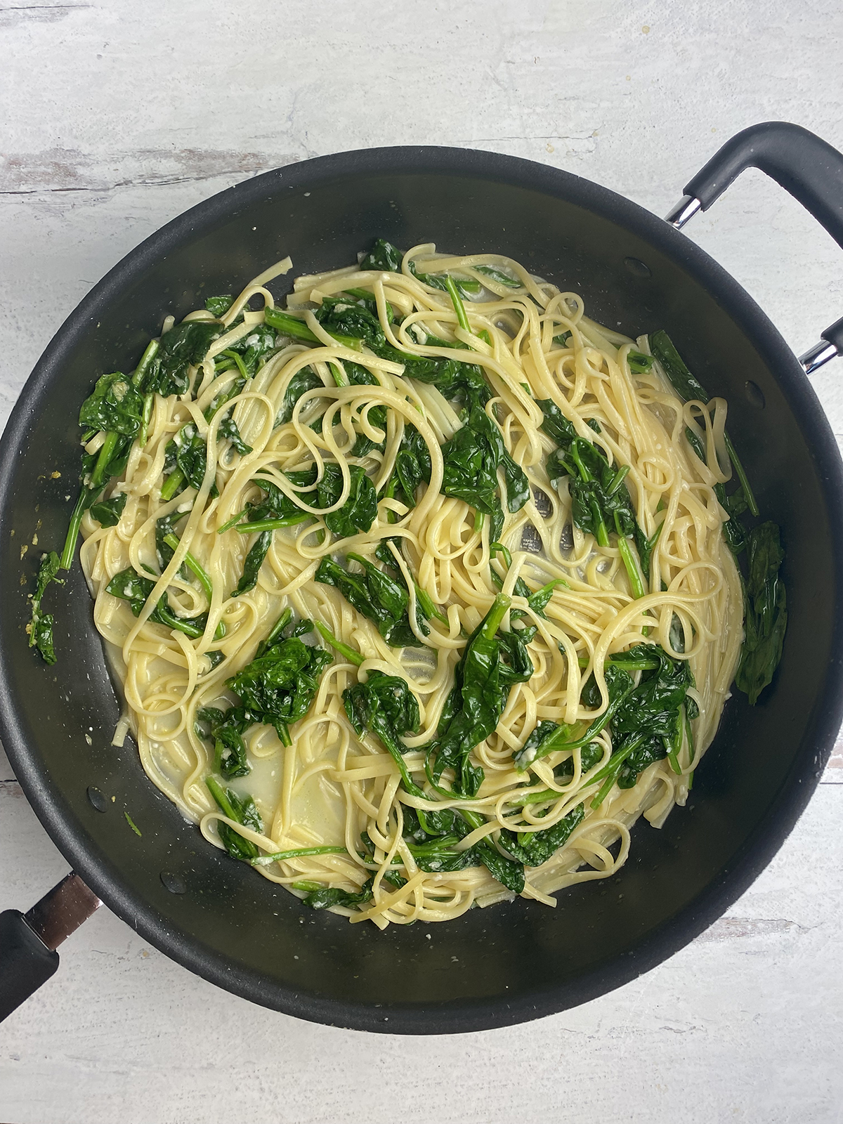 Finished lemon spinach pasta in a skillet.