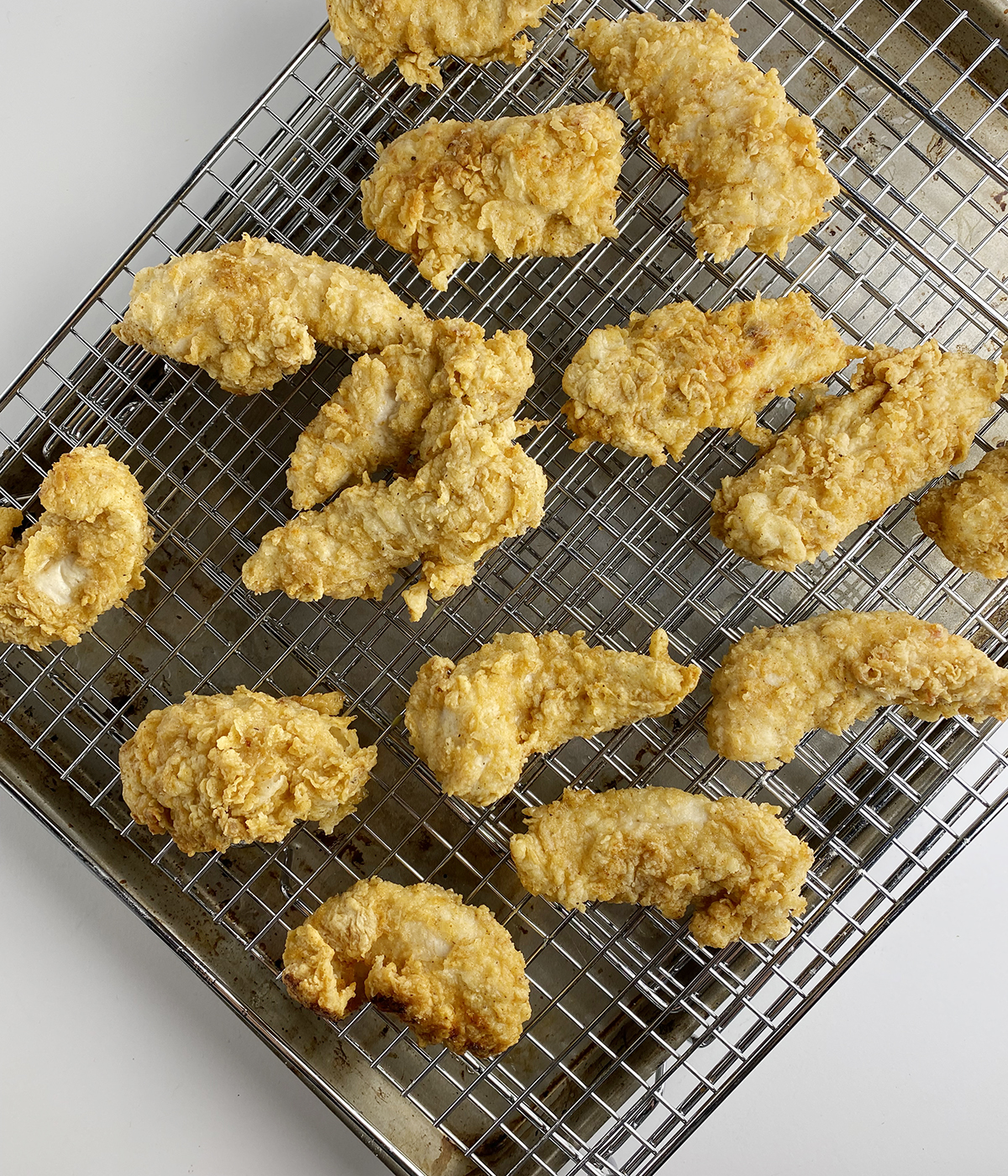 Buttermilk fried chicken tenders cooling on a rack.