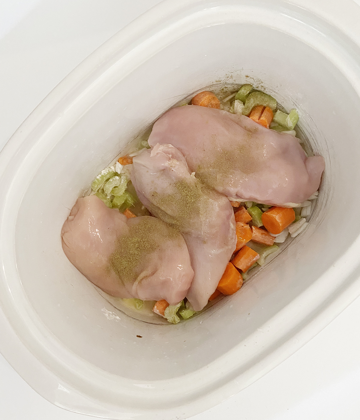 Chicken and vegetables in the slow cooker ready to be cooked.