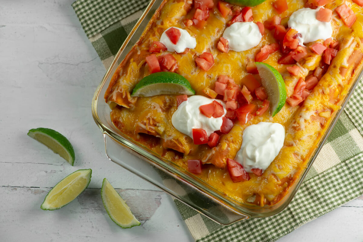 Creamy chicken enchilada casserole on a wooden board.