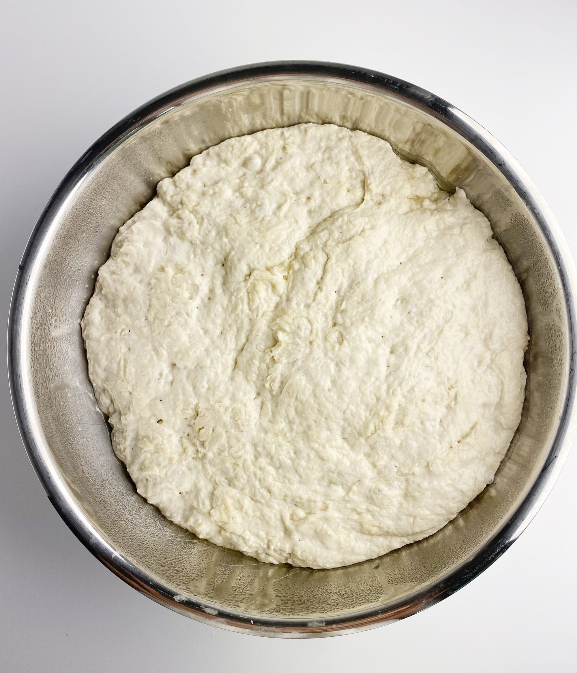 Focaccia dough first rise in a metal bowl.