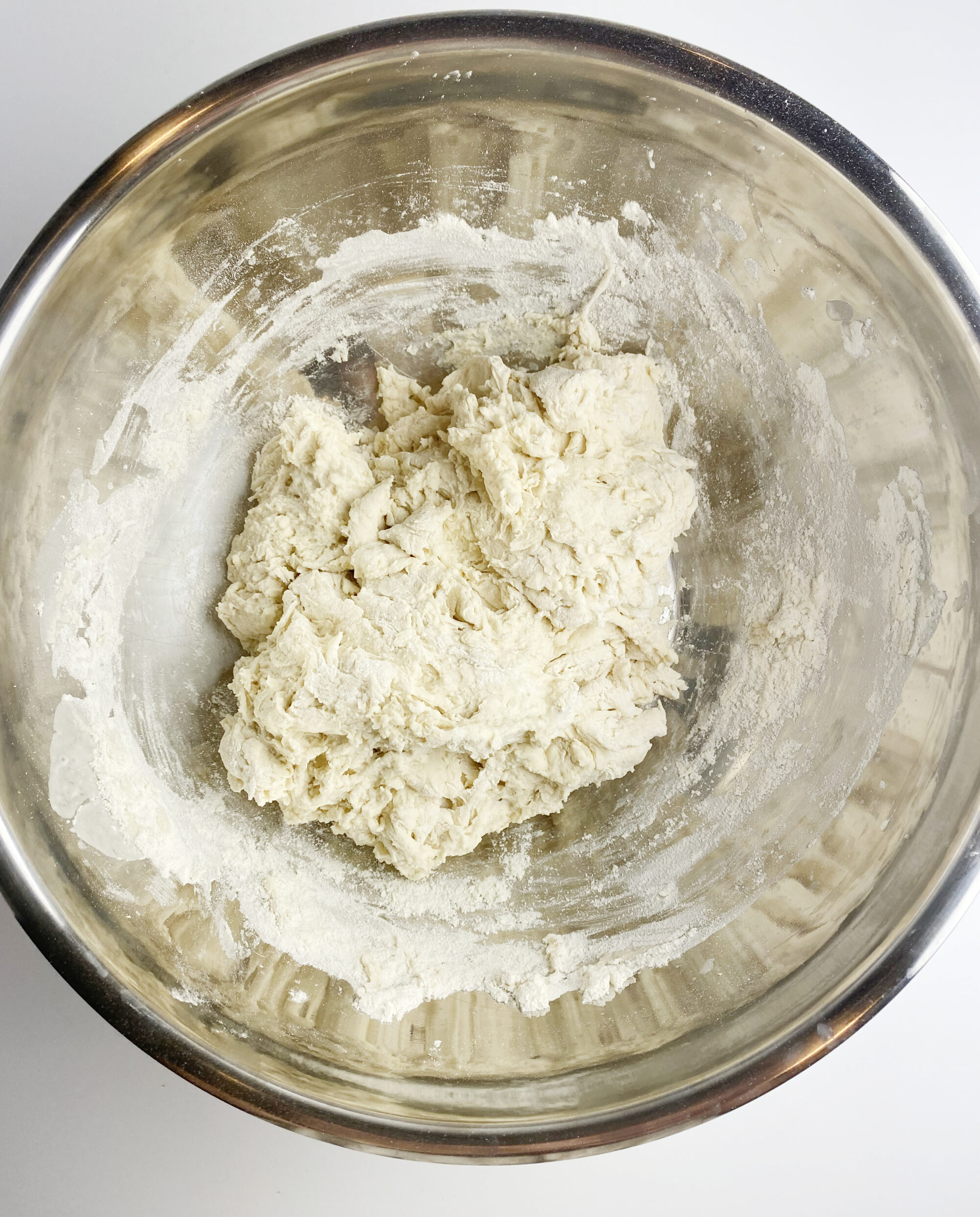 Focaccia dough in shaggy ball in a metal bowl.