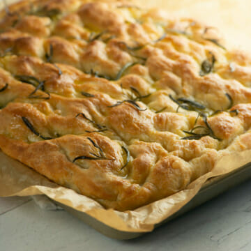 Baked focaccia in sheet pan with parchment.