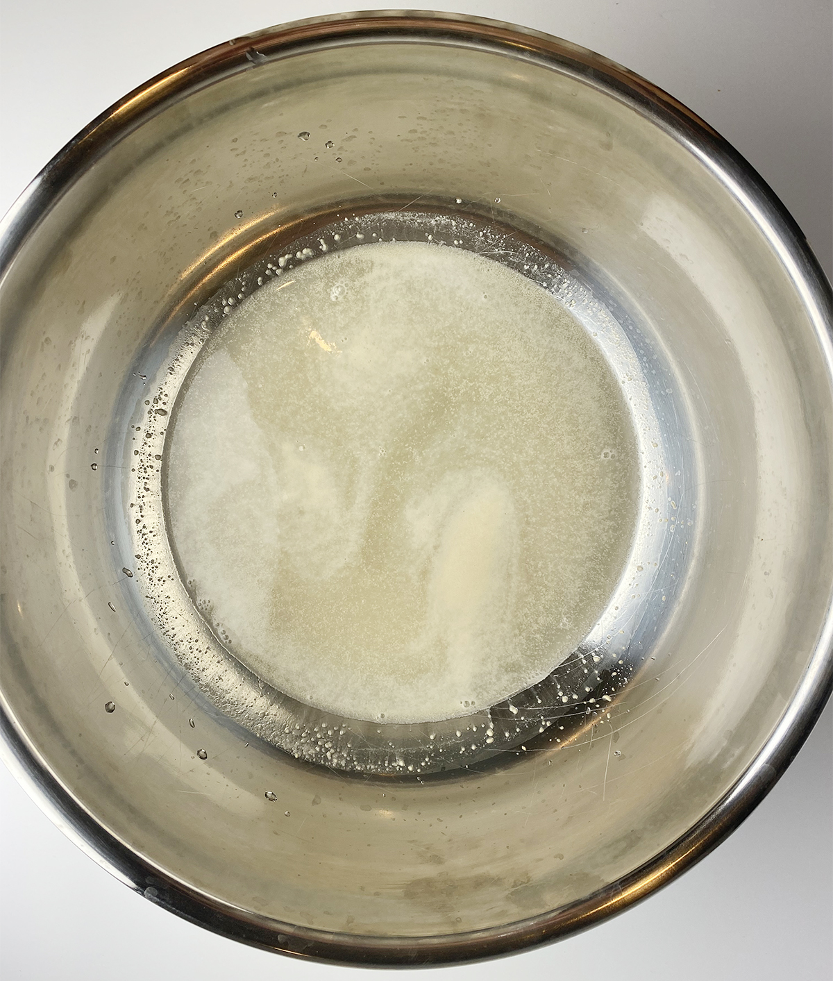 Bubbly yeast mixture in a metal bowl.