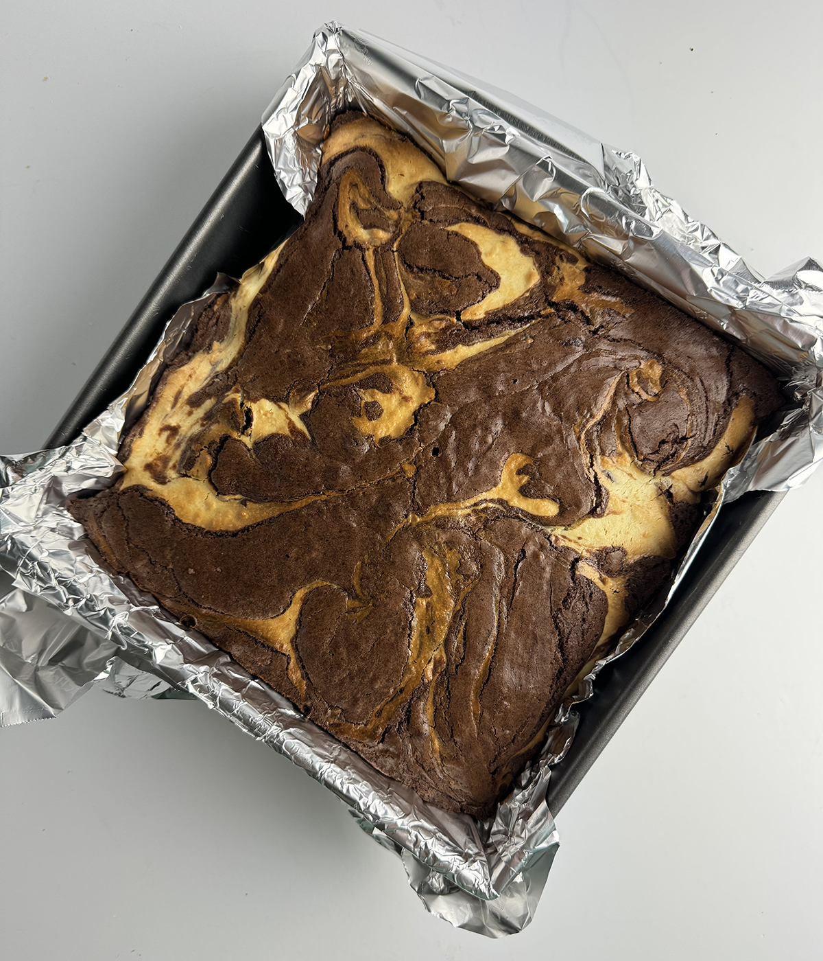 Baked cheesecake swirl brownies in a baking pan.