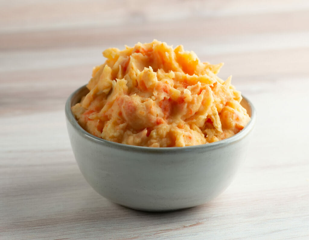 Carrot mashed potatoes in a bowl on the counter.