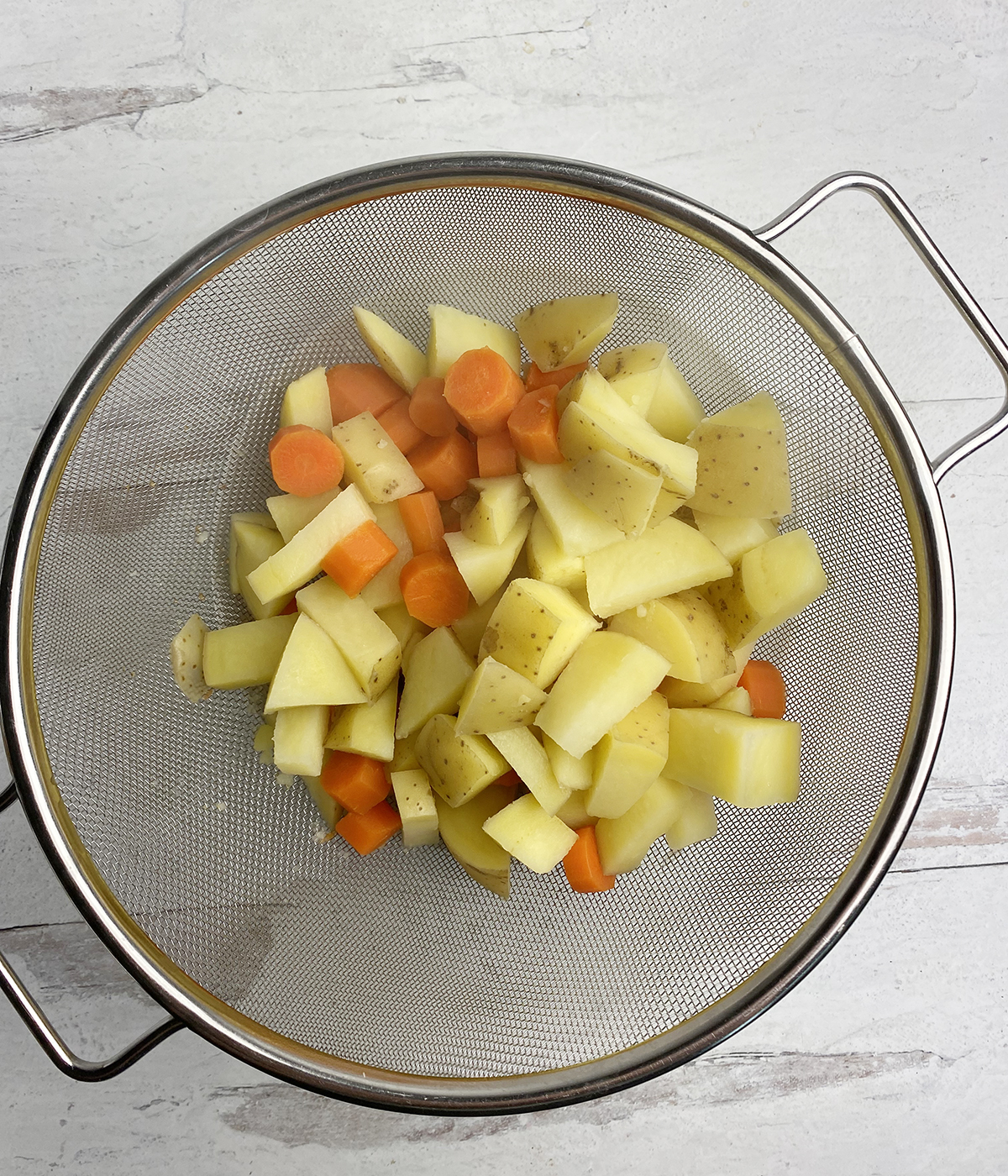 Carrots and potatoes cooling in a strainer.