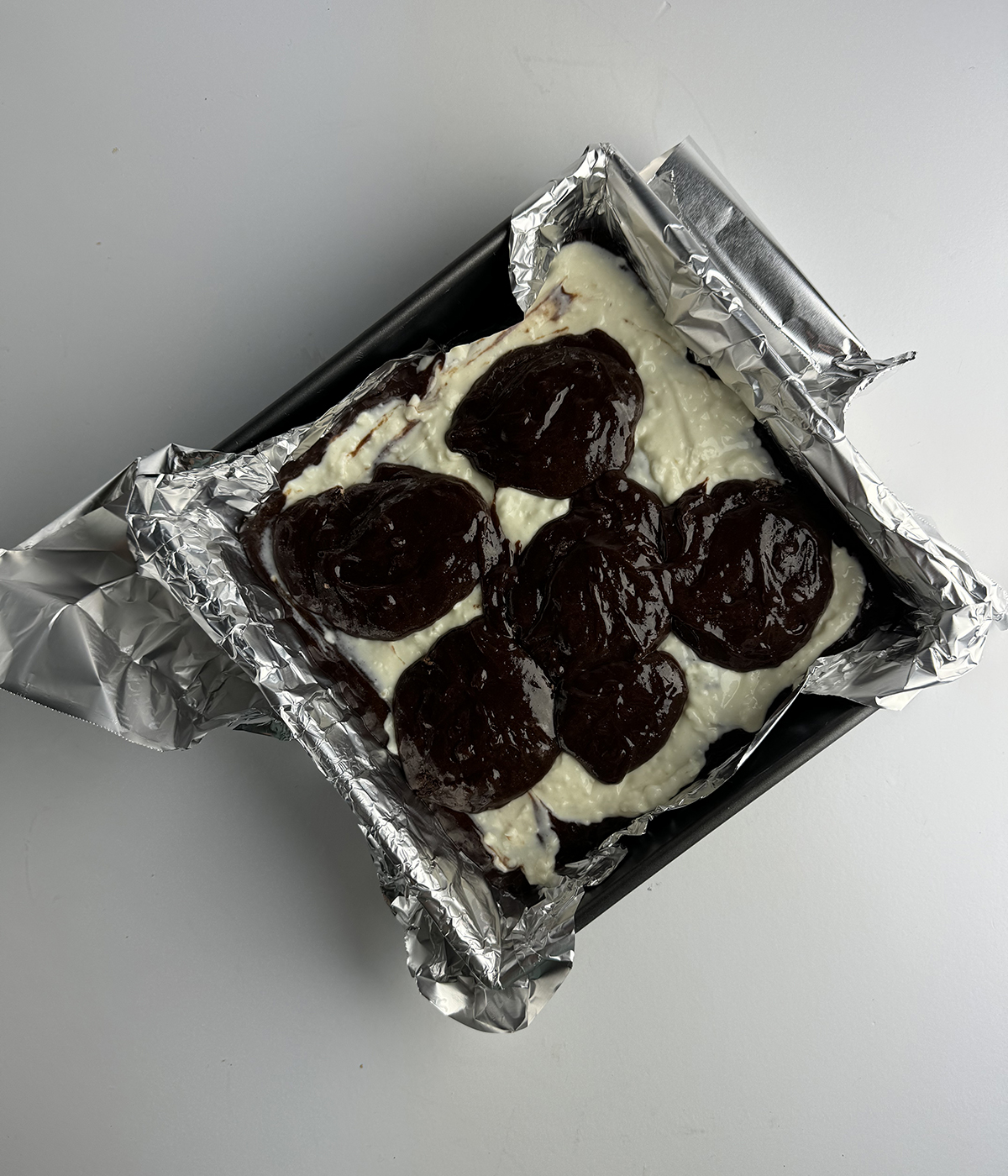 Cheesecake brownie batter in a pan.