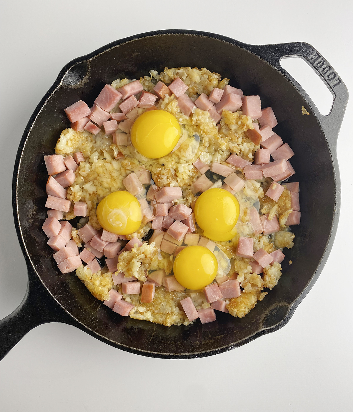 Eggs cracked onto the top of a ham and cheese breakfast casserole.