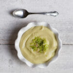 avocado vichyssoise in white bowl on white boards