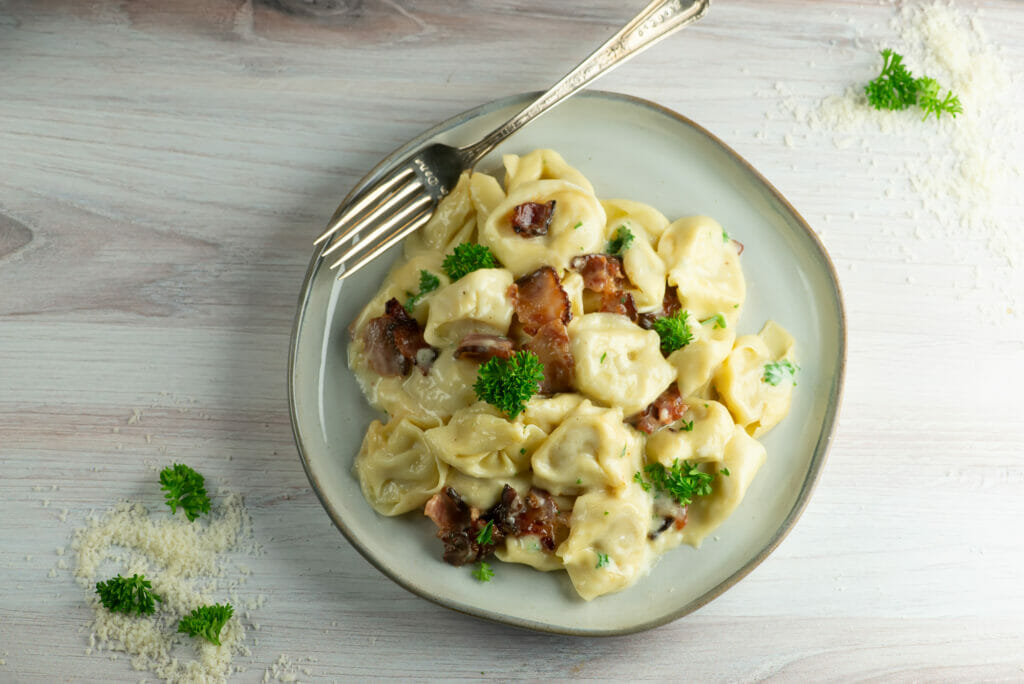 bacon tortellini alfredo on plate with fork