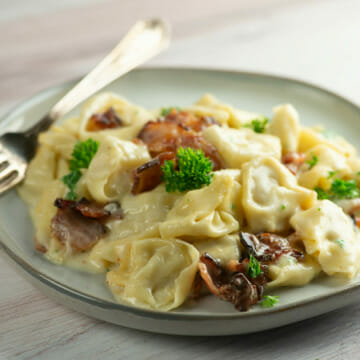 bacon tortellini alfredo on plate with fork