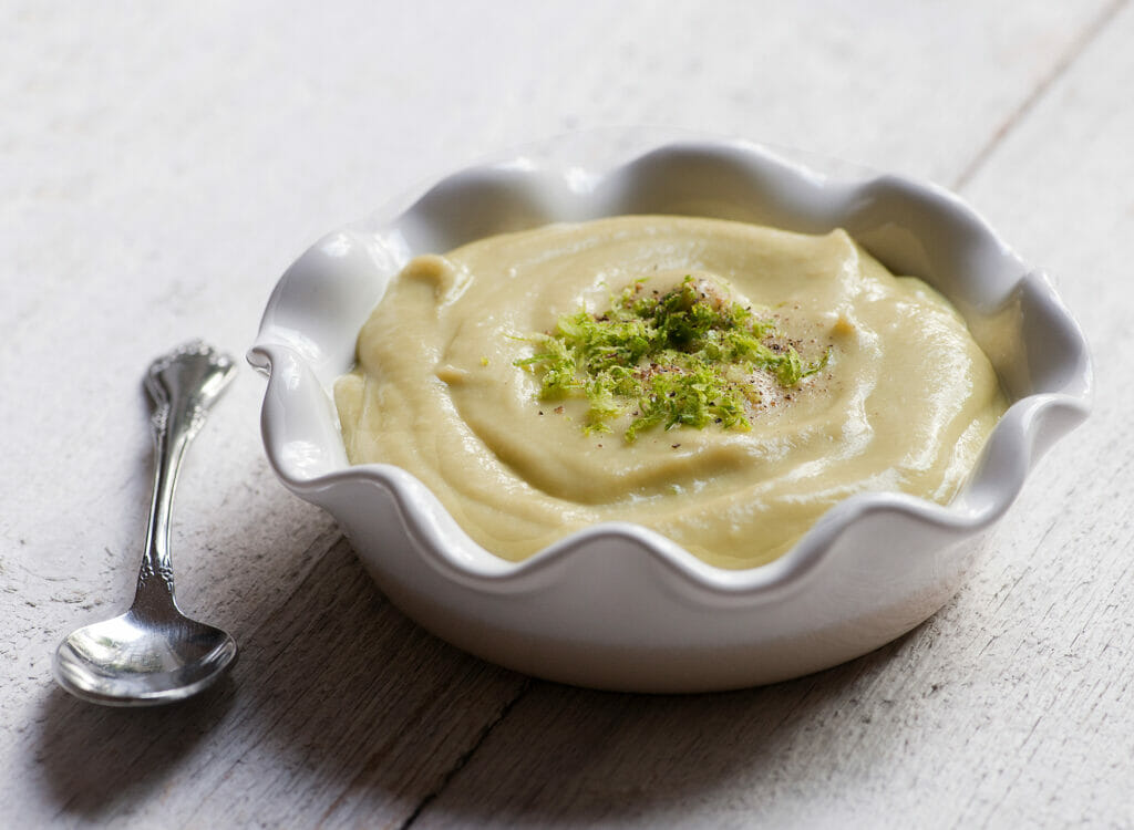 avocado vichyssoise in white bowl on white boards