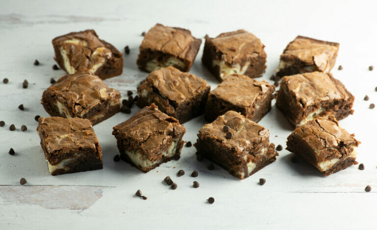 Cheesecake Swirl Brownies on a wooden counter.