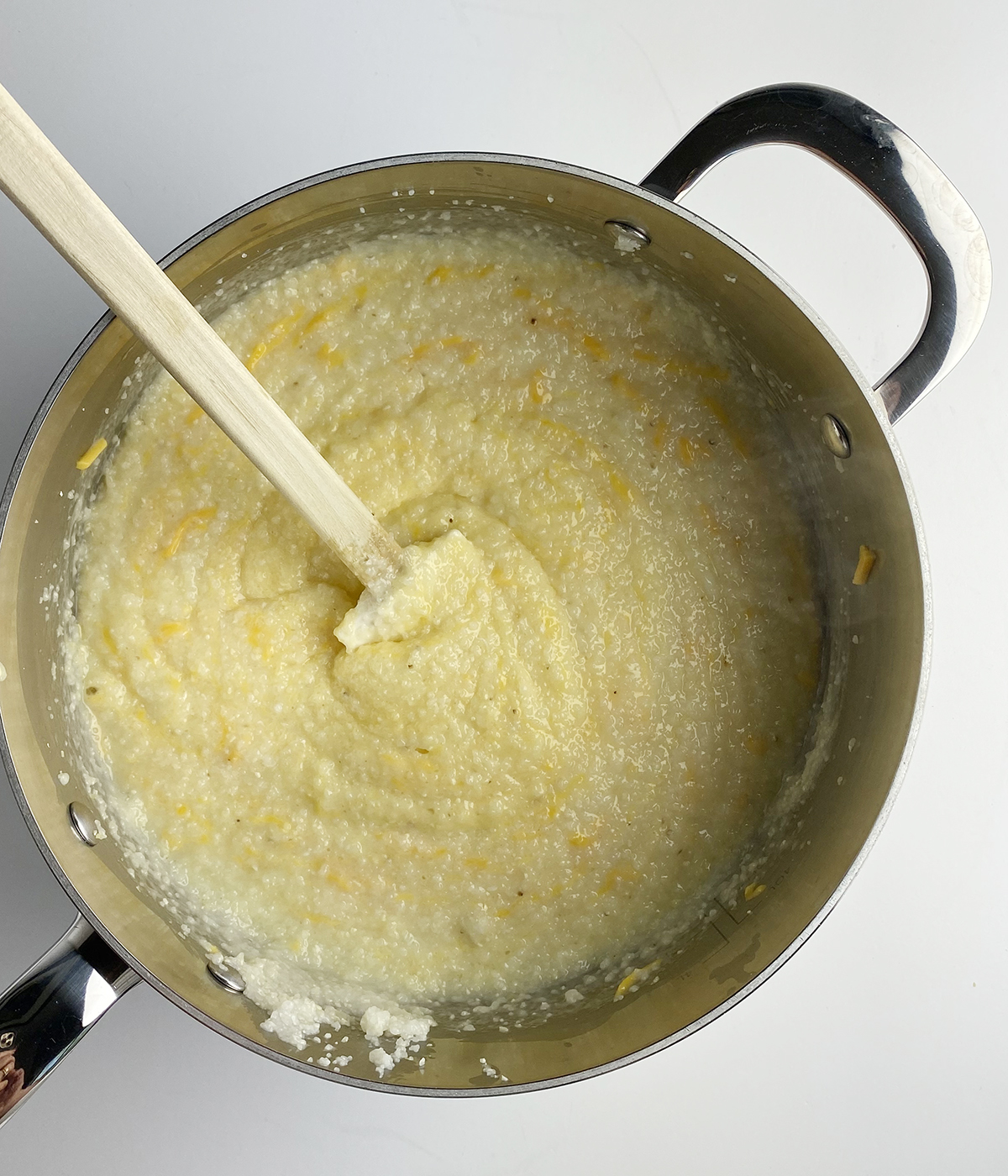 Cheese being stirred into a pot of grits.