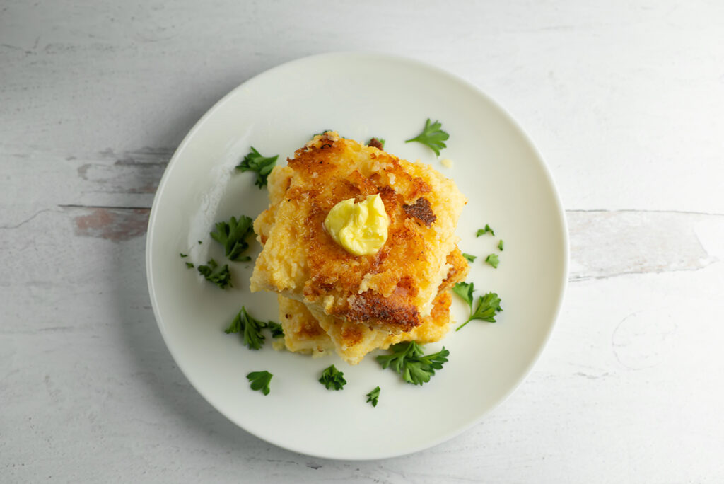 Cheesy grit cakes with butter on plate.