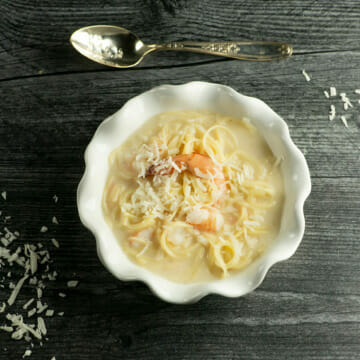 Coconut Shrimp Soup with spoon on grey board