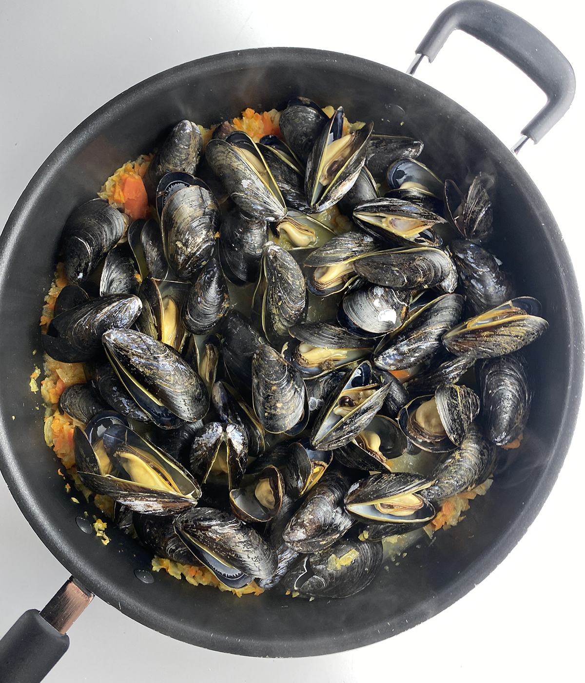Skillet full of cooked mussels.