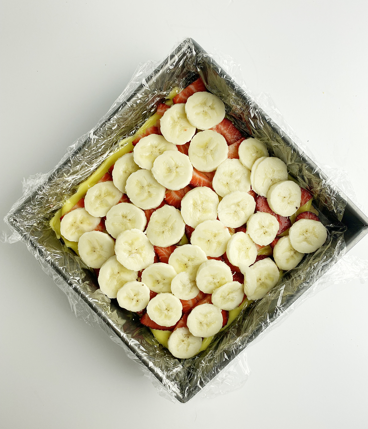 Strawberries and bananas and pudding layer of an icebox cake.